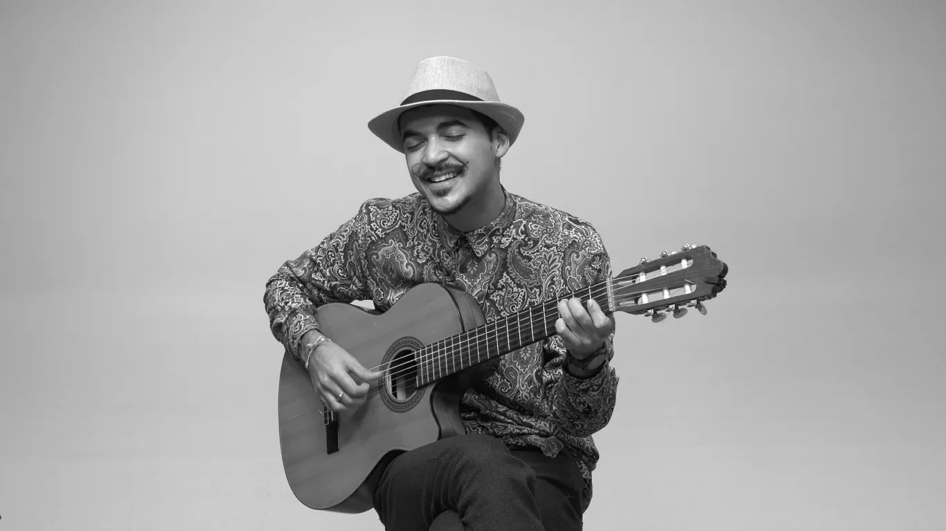 Matheus Fonseca assis en train de jouer de la guitare et de chanter