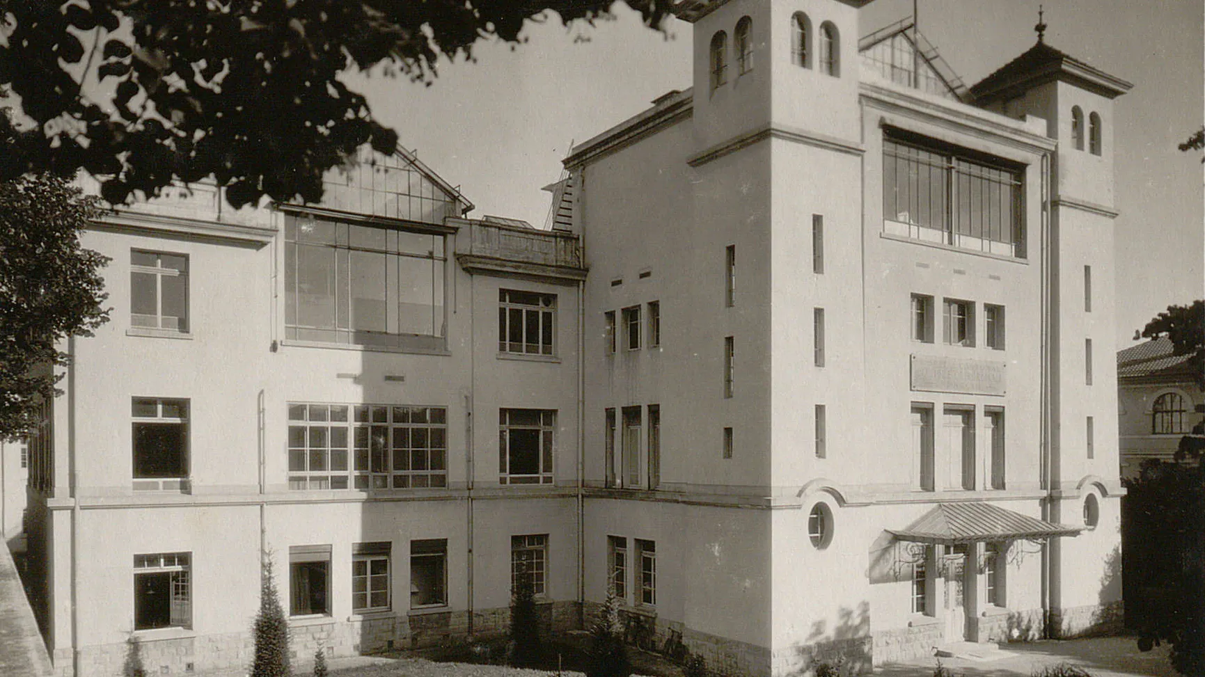 Bâtiment à plusieurs étages avec des tourelles, des grandes fenêtres et des toits partiellement vitrés.