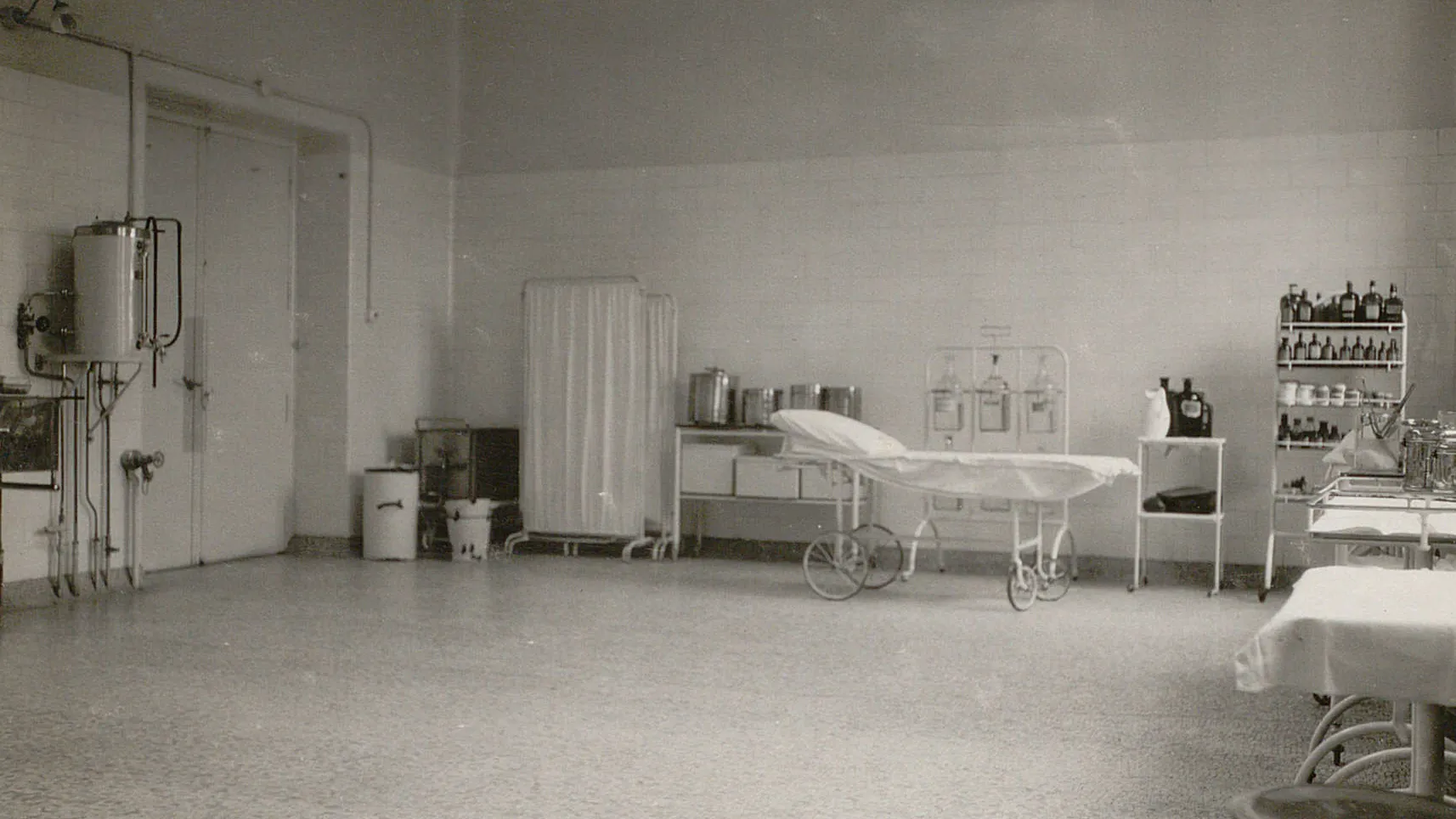 Table de traitement à grandes roues, tables d'appoint avec des flacons, des seaux etc., à gauche installation avec tuyaux.