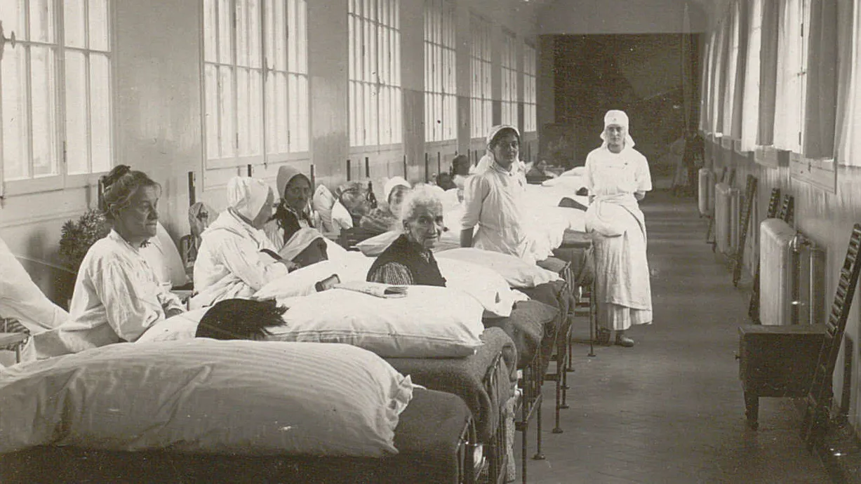 De nombreux lits sont alignés dans la grande passerelle, des femmes y sont assises ou alitées.