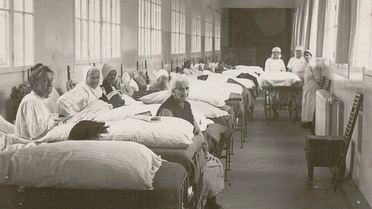 De nombreux lits sont alignés dans la grande passerelle, des femmes y sont assises ou alitées.