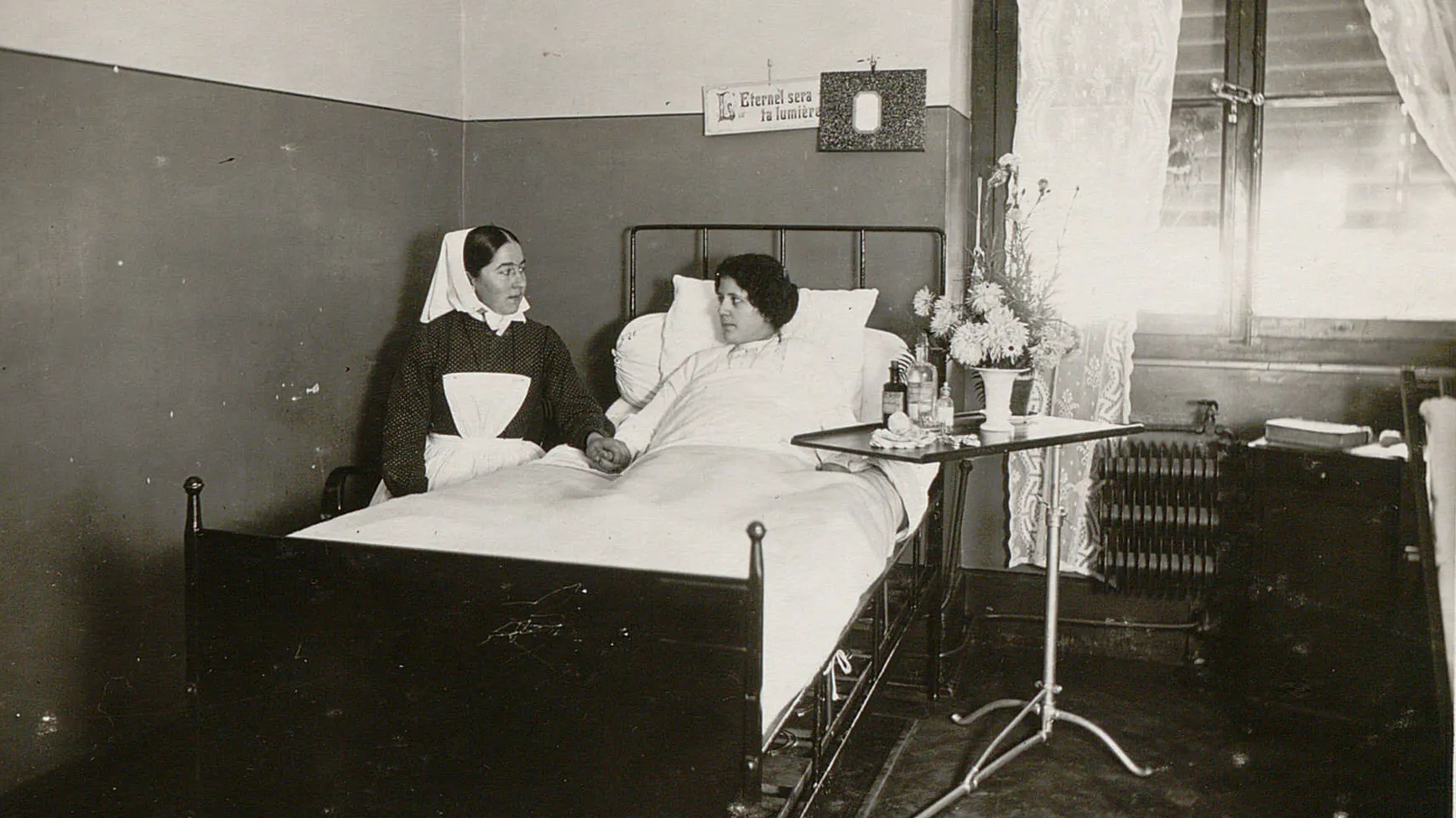 Une diaconesse tient la main d'une patiente alitée.