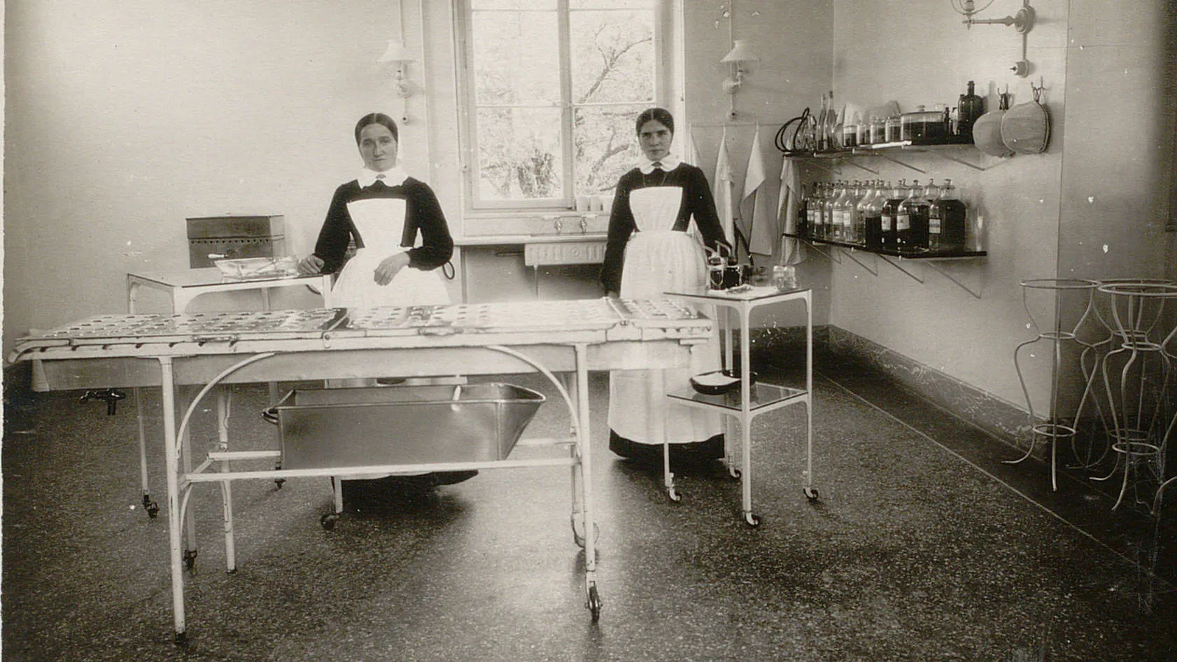 Deux diaconesses debout dans une pièce équipée de tables et étagères.