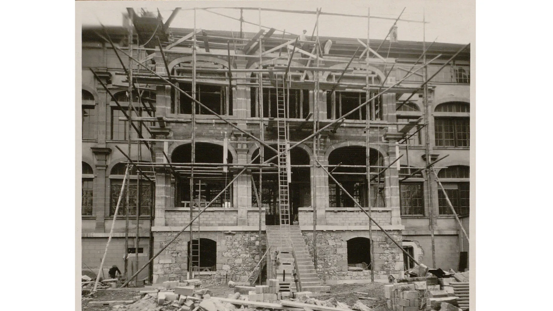 Un échafaudage devant une façade avec des grandes arches ouvertes (futures baies vitrées).