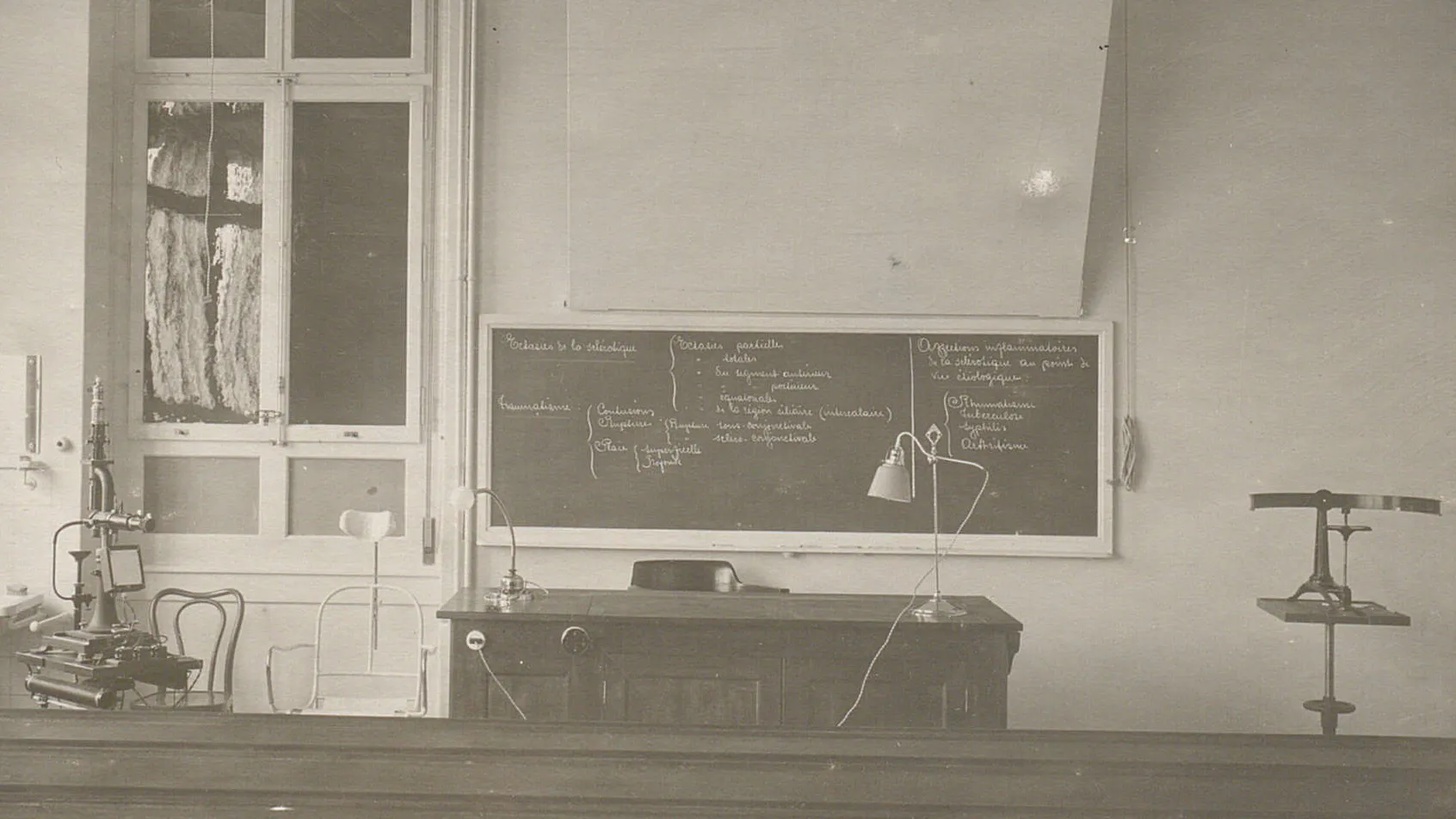 Salle de cours vide, un tableau noir avec des inscriptions, des appareils pour examen ophtalmologique.