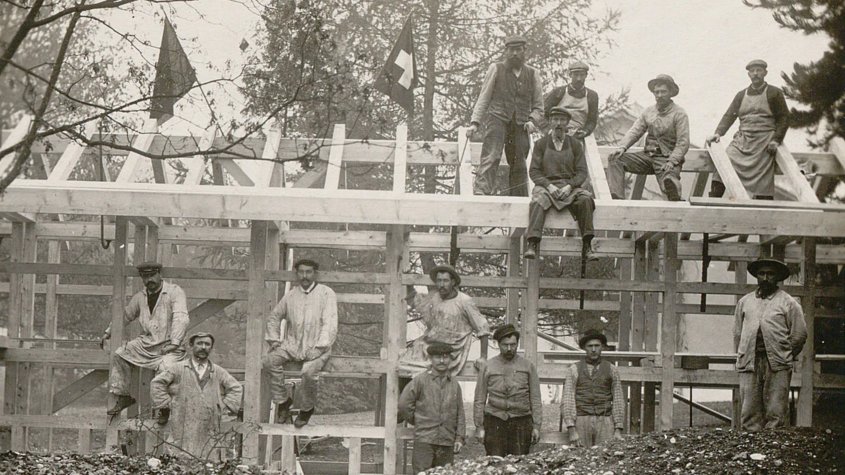Des ouvriers sur la charpente d'un pavillon en cours de construction.