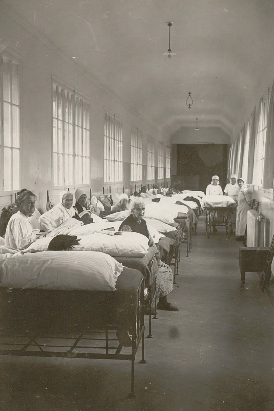 De nombreux lits sont alignés dans la grande passerelle, des femmes y sont assises ou alitées.