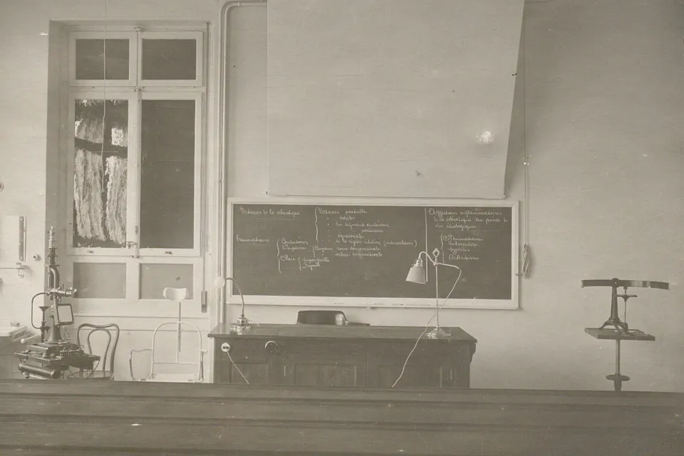 Salle de cours vide, un tableau noir avec des inscriptions, des appareils pour examen ophtalmologique.